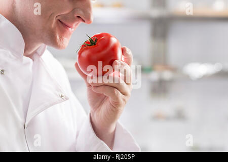 Sezione mediana del maturo cuoco odore fresco di pomodoro rosso permanente, mentre presso il ristorante cucina Foto Stock