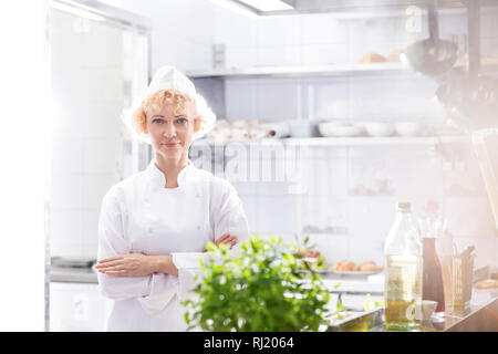 Ritratto di certi chef in piedi con le braccia incrociate in cucina al ristorante Foto Stock