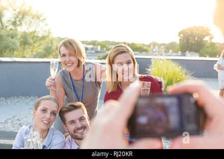 I colleghi sorridente in posa per uomini d'affari durante la festa sul tetto Foto Stock