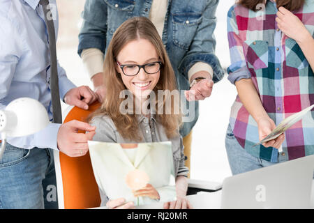 Creative imprenditrice cercando di fotografare durante il lavoro con i colleghi Foto Stock