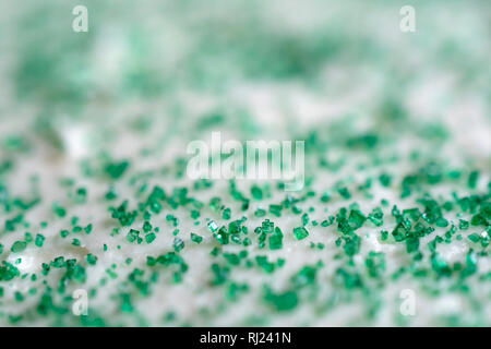 Estrema vista ravvicinata di verde di cristalli di zucchero su uno sfondo di glassa bianca. Copia dello spazio. Abstract background. Foto Stock