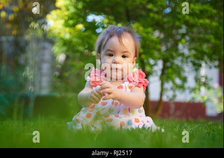 Ritratto di bambina seduta su erba verde sullo sfondo Foto Stock