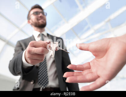 Immagine ritagliata di agente immobiliare di dare le chiavi di casa a uomo in ufficio Foto Stock