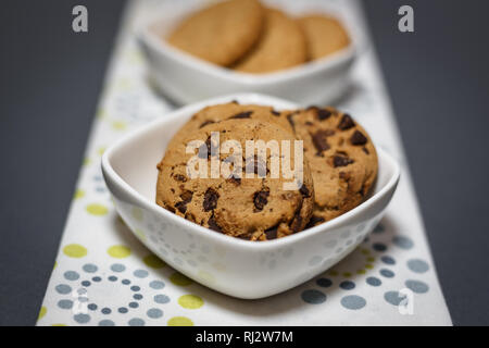 Vista ravvicinata di due diversi tipi di cookies, fiocchi d'avena e biscotti con scaglie di cioccolato bianco bocce. Foto Stock