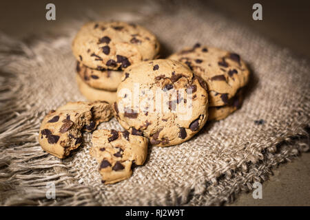 Freschi i biscotti al cioccolato appena sfornati in sfondo rustico. Vista da vicino con il fuoco selettivo. Foto Stock