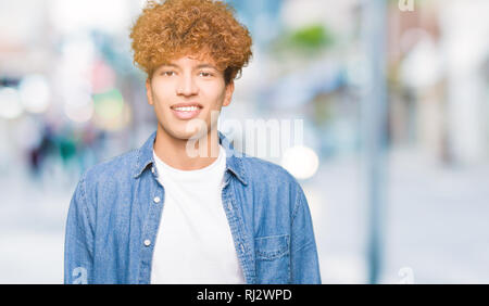 Giovane uomo bello con capelli Afro indossa camicia denim con una felice e fresco sorriso sul viso. Persona fortunata. Foto Stock