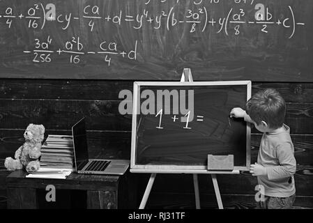 Il concetto di istruzione. Little Boy risolvendo l'equazione sulla lavagna. Formazione in età prescolare per smart kid Foto Stock