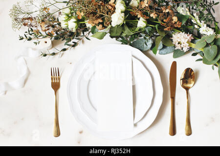 Nozze di festa di compleanno, impostazione tabella con golden posate, nastro di seta, rami di eucalipto, ortensie e rose bianche fiori. Scheda vuota mockup. R Foto Stock