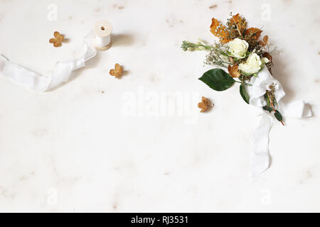 Inverno femminile matrimoni, compleanni ancora vita scena. Nastro di seta e mazzo di fiori secchi di foglie di acero, ortensie, rose bianche e gypsophila fiori, marmo Foto Stock