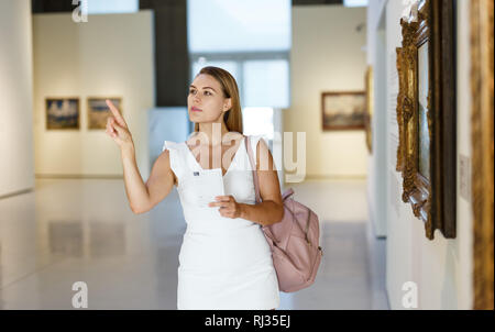 Giovani femmine visitatore di ammirare le opere in esposizione di dipinti nel museo Foto Stock