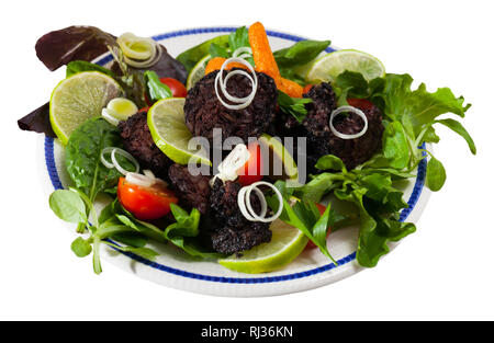 Gustoso budino nero salsiccia servita con verdure e cipolla e verdi su piastra. Isolato su sfondo bianco Foto Stock