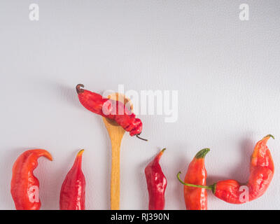 Fila di peperoncino rosso e il cucchiaio di legno su sfondo bianco con camera per spazio di copia Foto Stock