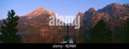 Stati Uniti d'America, Wyoming Grand Teton National Park, Sunrise sulla gamma Teton sopra Lake Jenny con il Grand Teton (sinistra), il Monte San Giovanni (a destra del centro) e ROC Foto Stock