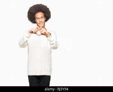 Giovane americano africano uomo con capelli Afro indossa occhiali sorridente in amore che mostra il simbolo del cuore e la forma con le mani. Concetto romantico. Foto Stock