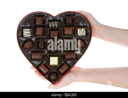 Mani a forma di cuore con scatola di cioccolatini isolati su sfondo bianco. Un popolare regalo per il giorno di San Valentino. Foto Stock