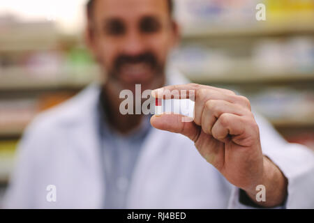 Il farmacista maschio tenendo una pillola. Close-up della mano che tiene una capsula di medicina. La cura della salute e la prevenzione del concetto. Foto Stock