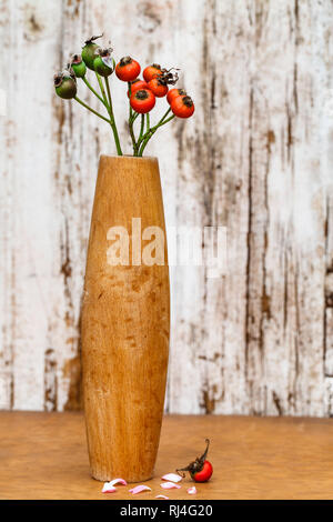 Stillleben mit Hagebutten in Holzvase Foto Stock