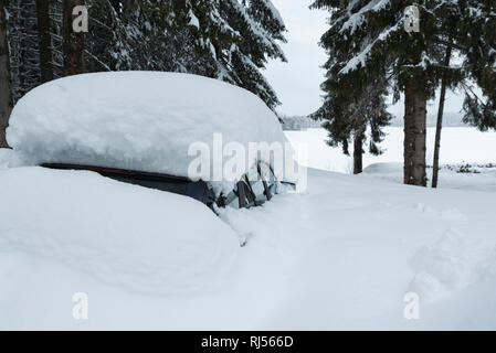 Un auto blu sotto la neve guidati in montagna tra i pini. Messa a fuoco selettiva Foto Stock