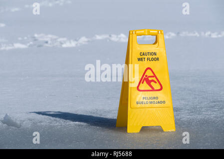 Un segno giallo bordo attenzione pavimento bagnato su un lago ghiacciato.  Messa a fuoco selettiva Foto stock - Alamy