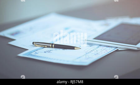 Tablet PC e grafici finanziari, penna giacente sul documento Foto Stock
