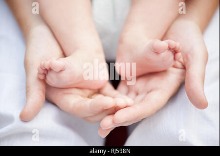 Dolce madre mani abbracciando i piedi del suo bambino, genitore amore, signor disponibili su richiesta Foto Stock