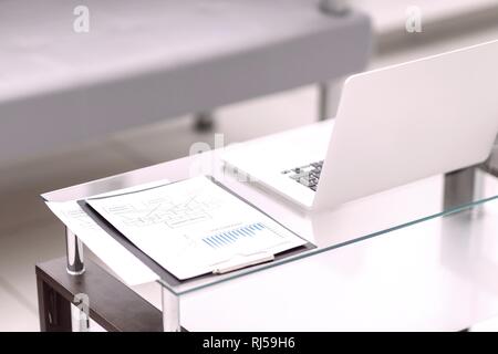 Laptop e grafici finanziari, penna giacente sul documento Foto Stock
