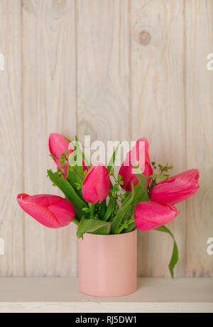 La molla bouquet di tulipani rosa con rami di un albero di fioritura di una luce sullo sfondo di legno. Messa a fuoco selettiva. Foto Stock