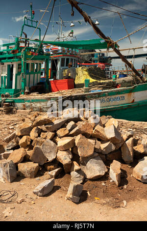 Cambogia, Preah Koh Kong, pietre di zavorra sul quay accanto a colorate barche da pesca Foto Stock