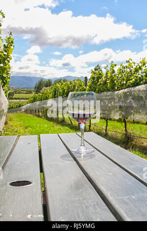 Il vetro con il vino rosso sul tavolo nel vigneto di Hawkes Bay, Nuova Zelanda Foto Stock