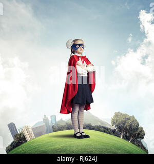 Girl power concetto con cute kid custode contro il paesaggio sullo sfondo Foto Stock