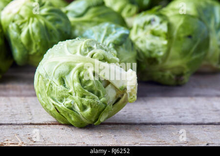 Fresche materie organiche cavoletti di Bruxelles sul rustico sfondo di legno Foto Stock