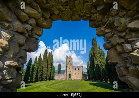 Castello di Romena si trova sulla cima di una collina, incorniciata da cipressi, visto attraverso un cancello roccioso Foto Stock