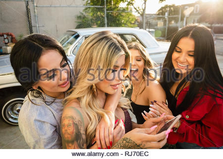 Latinx donne giovani amici utilizzando smart phone