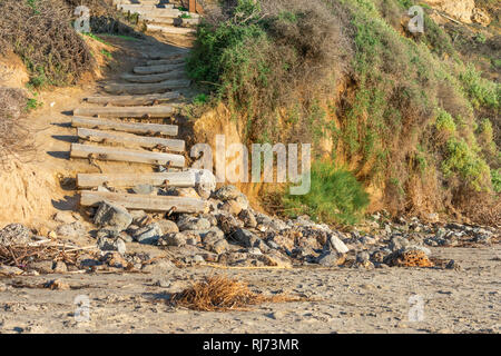 Vecchio weathered stair caso costituiti da tronchi di legno che conduce alla spiaggia, terminando sulle rocce Foto Stock