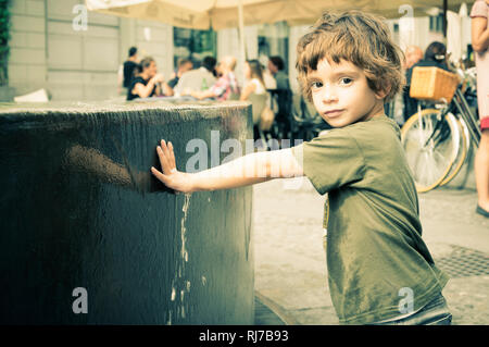 Bambino con maglione verde nel centro di Milano in autunno Foto Stock