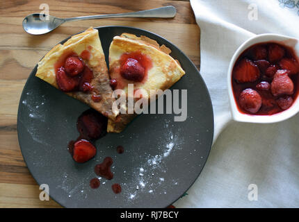 Pancake fatti in casa con ricotta e fragole su una piastra. Sfondo di legno. Foto Stock