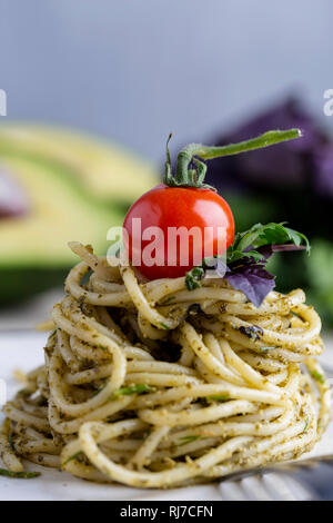 Freschi pomodori ciliegia sulla pila di pasta al pesto. Macro. Concetto di cucina italiana Foto Stock