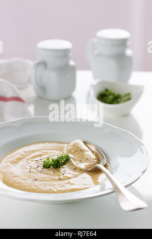 Crema di verdure minestra di patate, carote, funghi e formaggio in una piastra bianca su un tavolo bianco, closeup, il fuoco selettivo Foto Stock