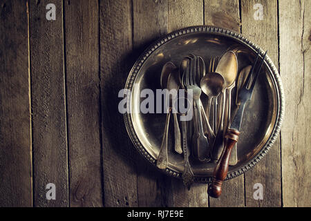 Vintage rustici e vecchi utensili da cucina forchette Cucchiai e coltelli sul vecchio tavolo in legno. Cibo o Vintage concetto rustico. Vista dall'alto. Foto Stock