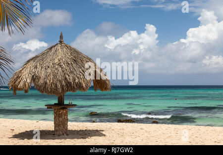 Con il tetto di paglia ombrellone sulla spiaggia Arashi, Aruba, Antille olandesi Foto Stock