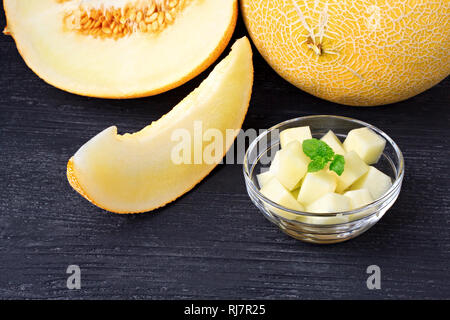 Dolci fresche melone arancione su un vecchio nero tavolo di legno(fuoco selettivo). Foto Stock