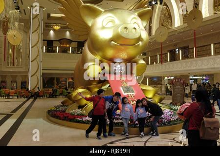 I turisti pongono di fronte a un gigantesco GoldenPig con ali per il Capodanno cinese in Galaxy Hotel e casinò di Macau SAR Foto Stock