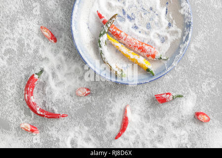 Bunte Chilischoten auf blauem Teller mit Meersalz Foto Stock