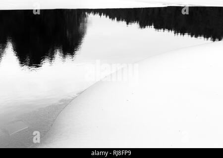 Schweden, inverno, Spiegelung im Wasser mit Eis, Schnee und Bäumen Foto Stock