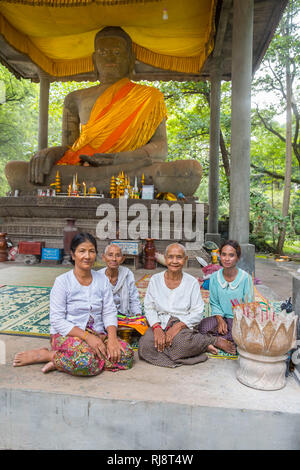 Siem Reap, Angkor, Tempel Baphuon, Betfrauen die um eine Buddhastatue herum sitzen und für Touristen gegen Geld Beten Foto Stock