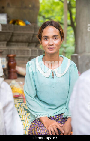 Siem Reap, Angkor, Tempel Baphuon, eine Frau die vor einer großen Buddhastatue sitzt und für Touristen gegen Geld betet Foto Stock