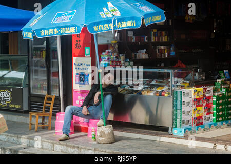 L'uomo addormentato nella parte anteriore del suo negozio Xingping, Guilin, regione, provincia di Guangxi, Cina Foto Stock