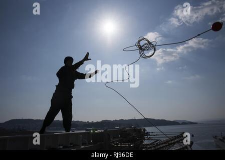 SASEBO, Giappone (nov. 3, 2016) Petty Officer di terza classe Zachary Yaros, da Huntington Beach, California, getta un appesantimento linea per linea pierside-gestori di assalto anfibio nave USS Bonhomme Richard (LHD 6) restituisce a Sasebo, Giappone. Bonhomme Richard servito come ammiraglia per Expeditionary Strike gruppo 7 durante un multi-mese patrol con i marines della trentunesima Marine Expeditionary Unit nel Indo-Asia regione del Pacifico. Foto Stock