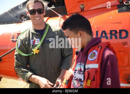 Petty Officer 2a classe Robyn Hamilton, una sopravvivenza di aviazione tecnico presso la guardia costiera Stazione aria Barbieri punto, Oahu, teens consente di provare sul suo ingranaggio di sopravvivenza durante un career day a Lanai alta e scuola elementare, Lanai, nov. 2, 2016. Parecchi membri dell'equipaggio dalla stazione aria Barbieri punto volato da Oahu a parlare con i bambini sulle possibili opportunità di carriera in guardia costiera e aviazione nonché fornendo un alto vicino guardare un MH-65 Delfino elicottero. Foto Stock