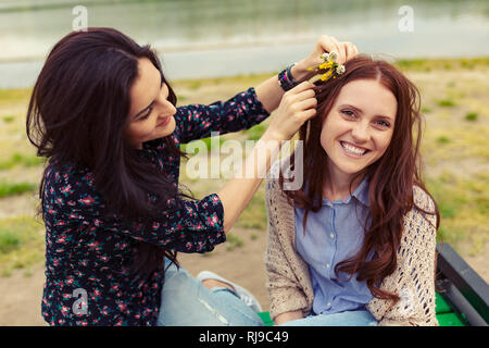 Due graziose sorelle ragazze divertirsi insieme, Campo dei fiori nei capelli, emozioni positive, colori luminosi. Foto Stock